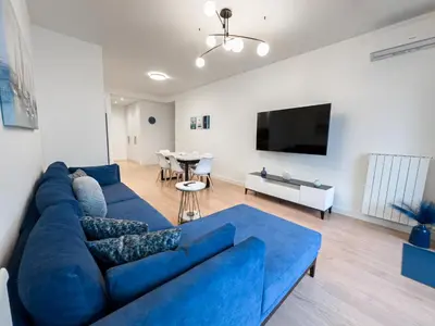 a living room with a blue couch and a table at Exceptional Belgrade Waterfront Apartment - Beograd na Vodi in Belgrade