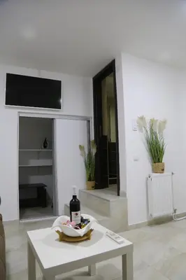 a white living room with a table and a tv at Studio T&M, sa parkingom in Obrenovac