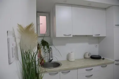 a white kitchen with a sink and a window at Studio T&M, sa parkingom in Obrenovac