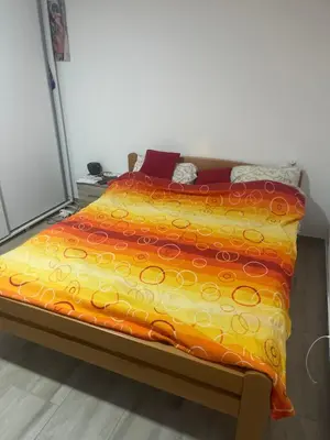 a bed with an orange and yellow blanket on it at Stan 3 UB in Ub