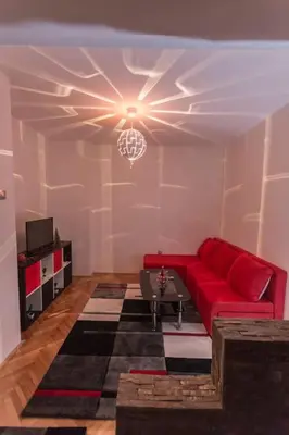 a living room with a red couch and a chandelier at Top of Pop in Belgrade