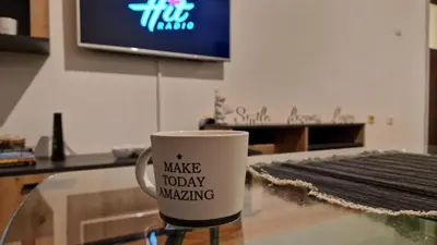 a coffee cup sitting on a glass table next to a tv at Apartman Dunja in Ruma