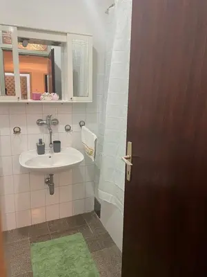 a bathroom with a sink and a mirror and a door at Apartman Dunja in Ruma