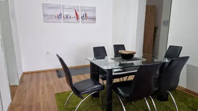 a dining room with a glass table and black chairs at Apartman Dunja in Ruma