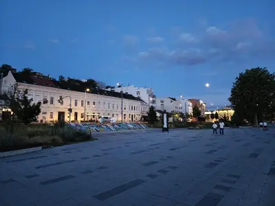 a city street at night with people walking around at Earth & Sky apartment in Sajmište