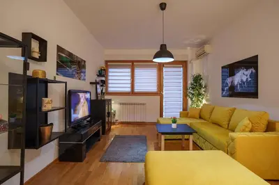 a living room with a yellow couch and a tv at Yellow Lux apartment in Novi Beograd