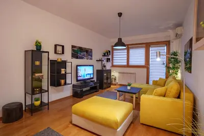 a living room with a yellow couch and a tv at Yellow Lux apartment in Novi Beograd