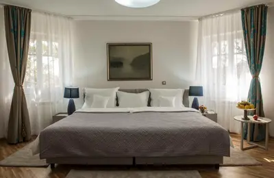 a bedroom with a large bed and two windows at Hotel Radmilovac in Belgrade