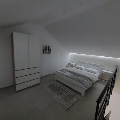 a white bedroom with a bed and a cabinet at Apartman LUX Jelena in Surčin