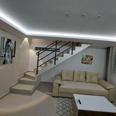 a living room with a couch and a staircase at Apartman LUX Jelena in Surčin