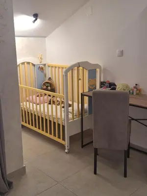 a crib in a room with a table and a tableablishangering at Apartman LUX Jelena in Surčin