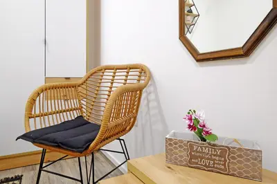 a wicker chair sitting next to a table with a mirror at Apartment Paradise Nice Home in Belgrade
