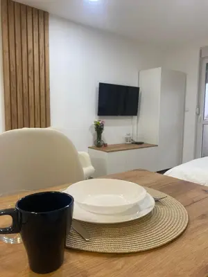 a plate on a table with a cup and a coffee mug at Apartman Enigma in Ruma