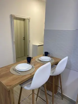 a wooden table with two chairs and plates on it at Apartman Enigma in Ruma