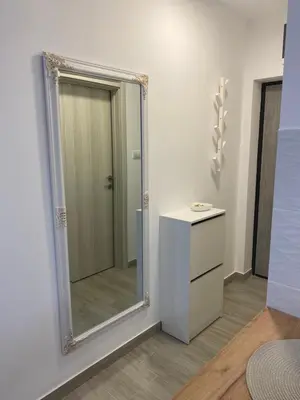 a mirror in a room with a dresser and a bathroom at Apartman Enigma in Ruma