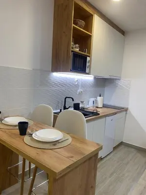 a kitchen with a wooden table and white cabinets at Apartman Enigma in Ruma