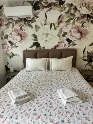 a bed with towels on it with a floral wallpaper at Apartman Enigma in Ruma