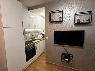 a kitchen with a flat screen tv on a wall at Apartman Savamala Promenada 57 in Belgrade