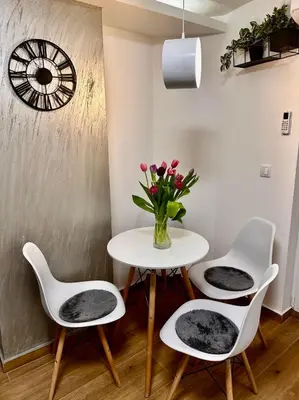 a table with three chairs and a vase with flowers at Apartman Savamala Promenada 57 in Belgrade