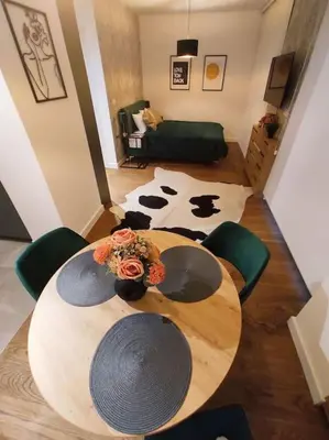 a wooden table with green chairs and a cow rug at Aria in Belgrade