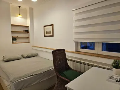 a bedroom with a bed and a table and a window at Apartment Olga in Vračar (historical)