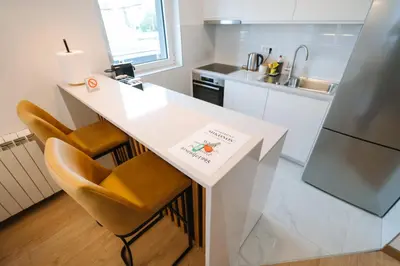 a white kitchen with a counter and a refrigerator at Nika apartman in Surčin