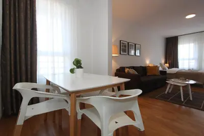 a living room with a table and two white chairs at Evergreen - studio in Belgrade to relax and enjoy, parking 5 eur per day in Belgrade