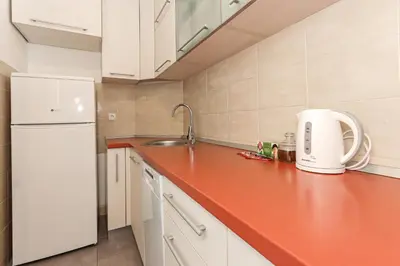 a kitchen with white cabinets and a red counter top at Fortuna - cozy studio to relax Novi Beograd, parking 5 eur per day in Belgrade