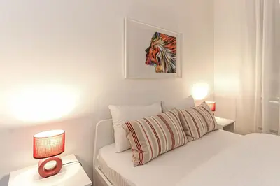 a white bedroom with a bed and two tables with lamps at Fortuna - cozy studio to relax Novi Beograd, parking 5 eur per day in Belgrade