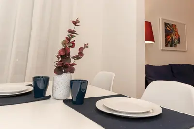 a white table with plates and a vase with flowers at Fortuna - cozy studio to relax Novi Beograd, parking 5 eur per day in Belgrade