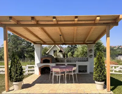 a wooden pergola with a table and chairs under it at Vila blizu Beograda - My Family Cottage in Ba°evac