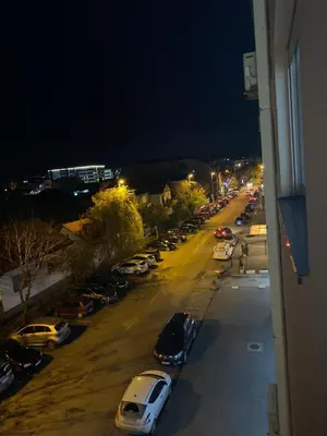 a view of a street with parked cars at night at Apartman Alexandra in Ruma