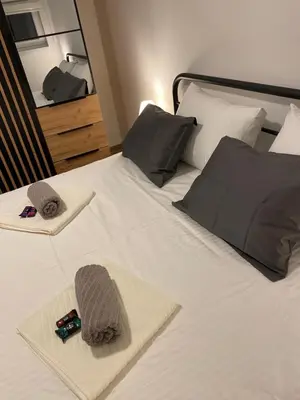 a bedroom with a bed with towels and a mirror at Apartman Alexandra in Ruma