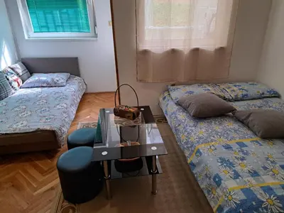 a room with two beds and a table with a chair at Apartman Mirka 2 in Karaburma