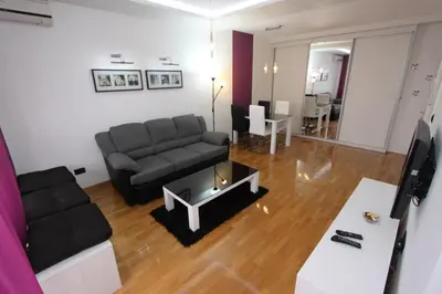 a living room with a black couch and a table at Aleksandar - Stan Na dan Belvil Novi Beograd in Belgrade