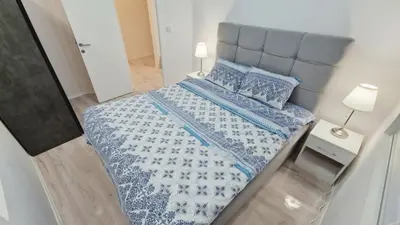 a small bedroom with a bed with a blue comforter and pillows at Zeus in Zemun