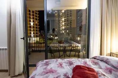 a bedroom with a bed and a balcony with a table at Belgrade Waterfront Cozy Symphony 1 in Sajmište