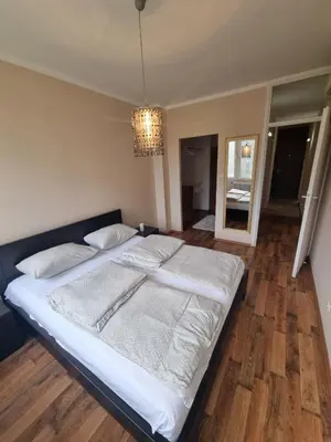 a large bed in a bedroom with a chandelier at Hawaii- 2 bdr, Arena, Sava centar, FREE PARKING in Novi Beograd