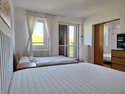 a white bedroom with a large bed and a window at RIVIJERA GREEN in Belgrade