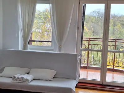 a living room with a couch and two large windows at RIVIJERA GREEN in Belgrade