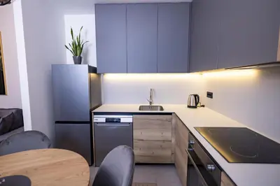 a kitchen with blue cabinets and a table and chairs at Belgrade Waterfront Cozy Symphony 2 in Sajmište
