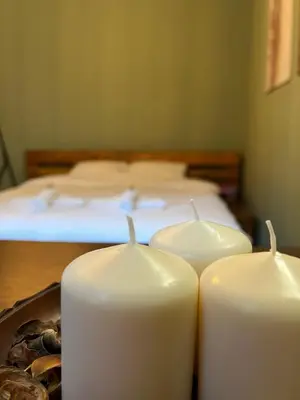 three candles sitting on a table in front of a bed at Under the Pine in Belgrade
