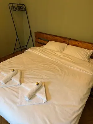a white bed with two towels on top of it at Under the Pine in Belgrade