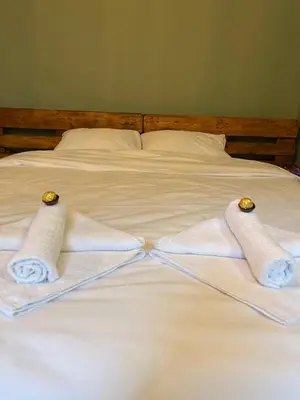 two towels are sitting on a white bed at Under the Pine in Belgrade
