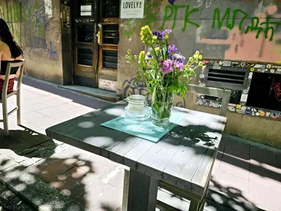 a vase of flowers sitting on a wooden table at Apartman Didi in Belgrade