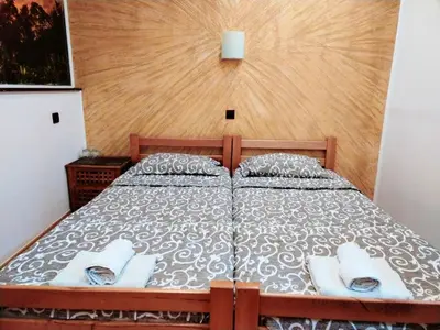 a bedroom with a bed with a wooden head board at FUN ROOMS SOBE PRENOĆIŠTE in Borča