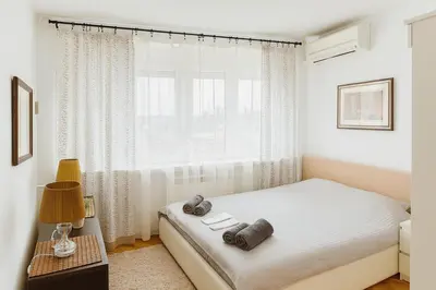 a white bedroom with a bed and a window at ART residence Cara Urosa in Belgrade