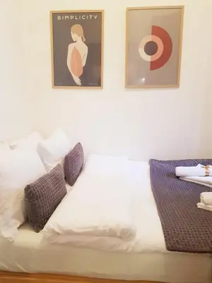 a white bed with two pictures on the wall at Beogradjanka CITY CENTAR cozy apartment in Belgrade