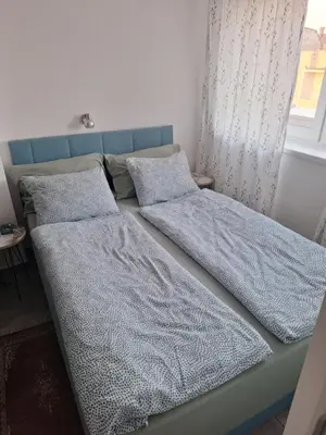 two beds in a bedroom with blue sheets and pillows at Apartman u Zemunu in Zemun