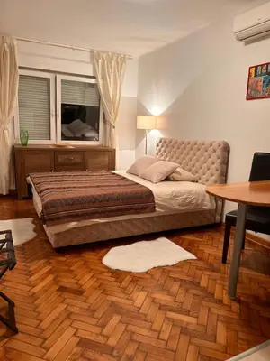 a bedroom with a bed and a table and a window at Cozy with parking in Zemun